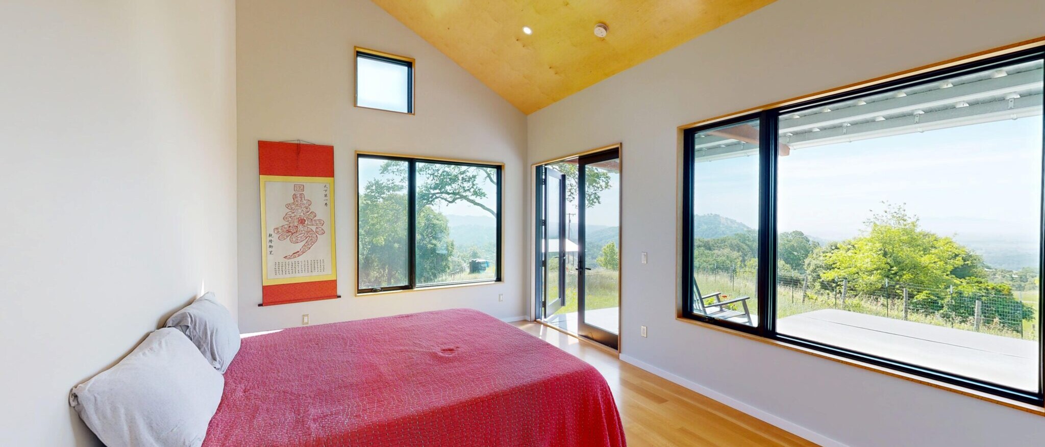 Custom modern bedroom with panoramic views in a Napa home, built by Black Creek Builders, featuring large windows and wood ceilings.
