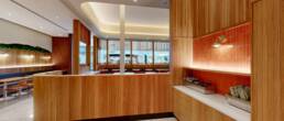 Modern restaurant interior with custom wood service counter, curved walls, and a view into the dining area and mall, built by Black Creek Builders.