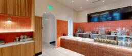 Modern restaurant service counter with orange tile accents, wood paneling, and an arched entryway, built by Black Creek Builders.
