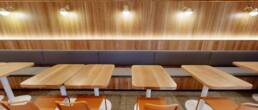 Modern restaurant dining area with long banquette seating, wooden tables, and a unique undulating green wall decor, built by Black Creek Builders.