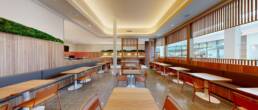 Spacious modern restaurant interior with banquette and table seating, unique wall decor, and wooden slatted partitions, built by Black Creek Builders.